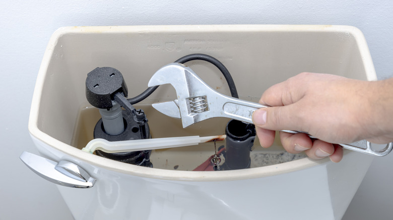 person using a wrench on toilet fill valve