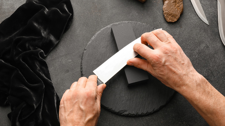 person sharpening knife on whetstone