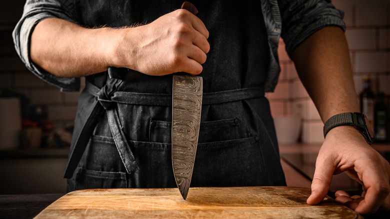 chef holding knife to cutting board