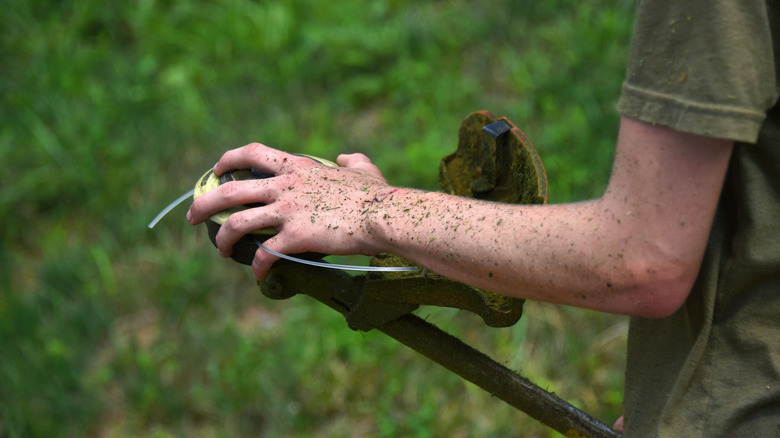 Hand removing weed eater spool cover