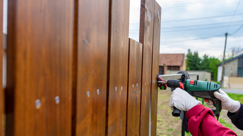 Person installing a brown wooden fence