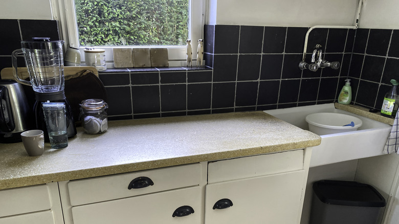 A taupe laminate countertop is installed in a dated kitchen