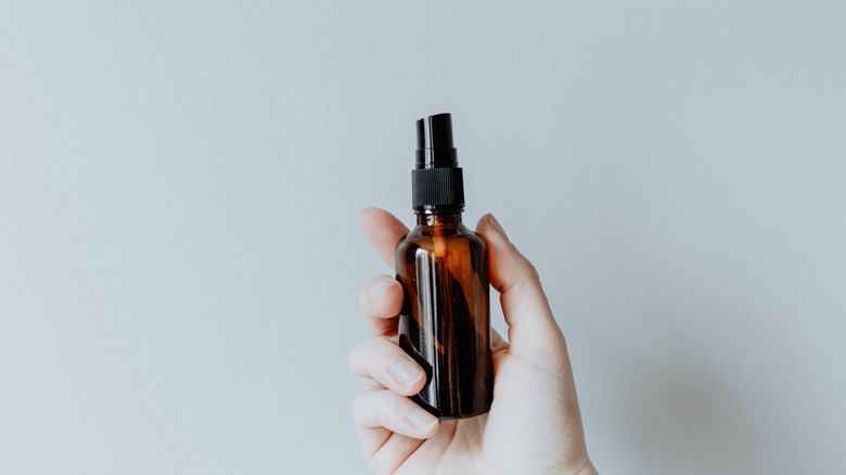 woman holding glass linen spray 