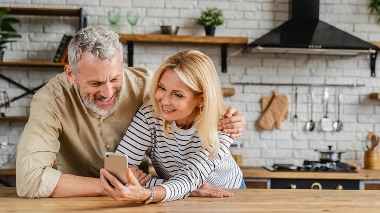 Couple sharing phone in kitchen