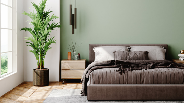 A bedroom with a light green accent wall behind the bed