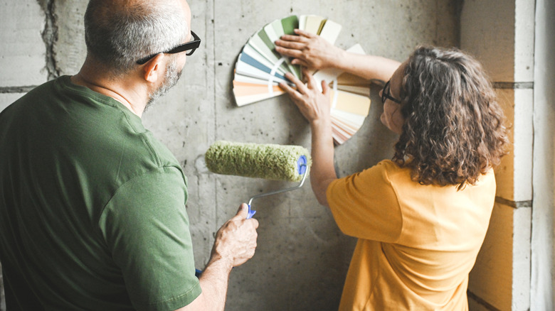 Man and woman looking at paint swatches on gray wall