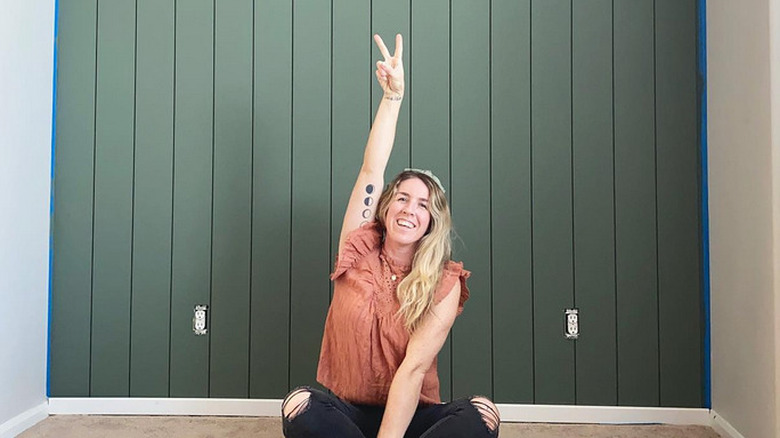 A woman sitting in front of a paneled wall with Sherwin Williams' Rosemary Paint