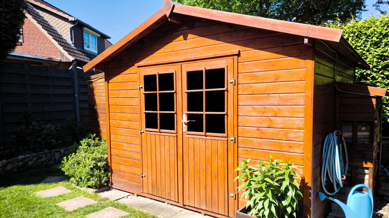 Side view of wooden garden shed glazed in teak color
