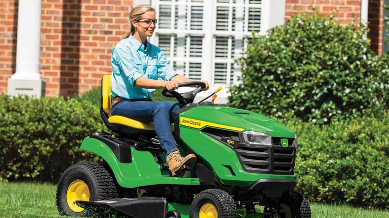 A person riding a John Deere lawn tractor