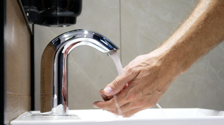 Person washes hands at touchless faucet