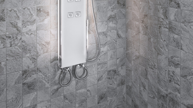 Metal digtal shower against gray tiles