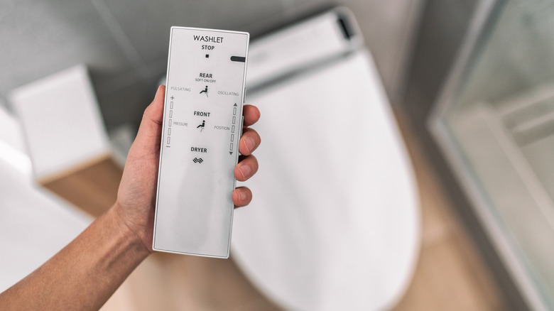 Man holding remote near smart toilet