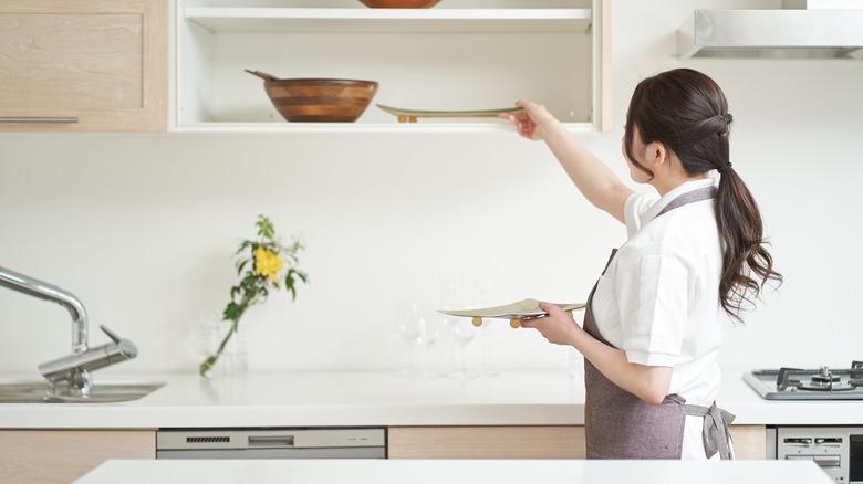 Woman putting plates away near dishwasher