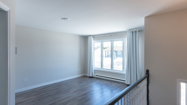 Empty room with dark wood floors and white curtains