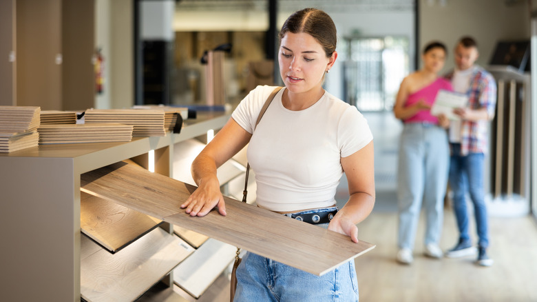 Woman choosing a wood panel in a store.