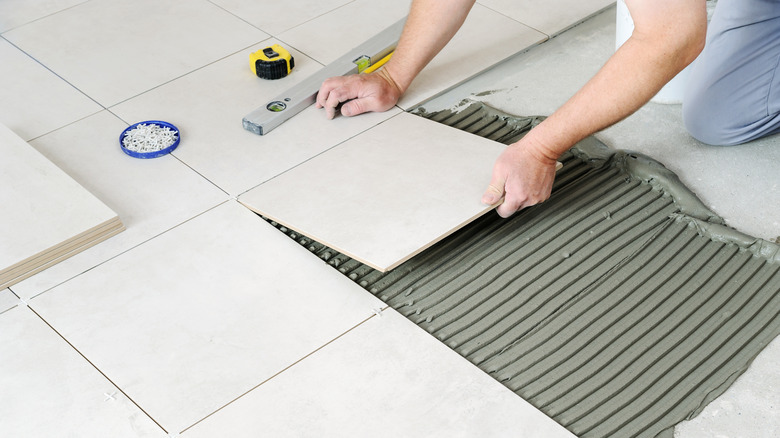 Hands installing ceramic tile