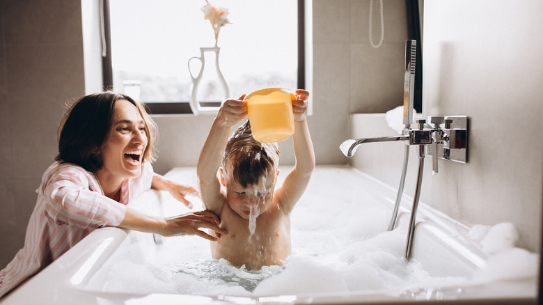 woman washing baby in bathtub 