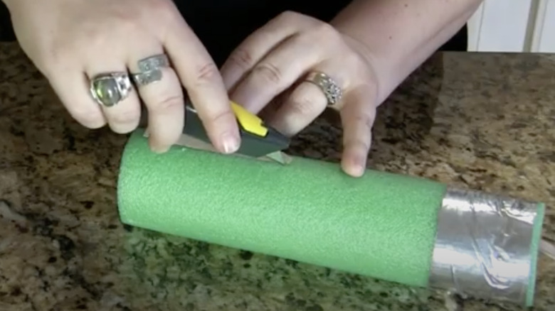 woman cutting pool noodle with utility knife