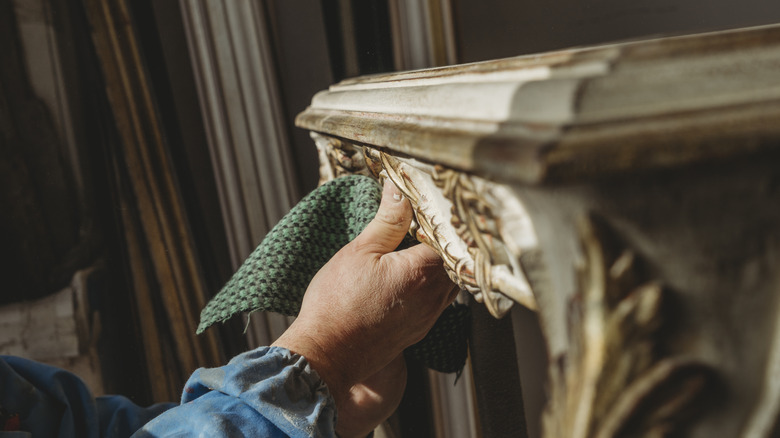 Person wiping down detailing on carved furniture