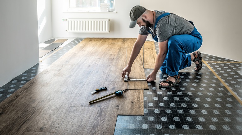 A person installing planks of vinyl flooring