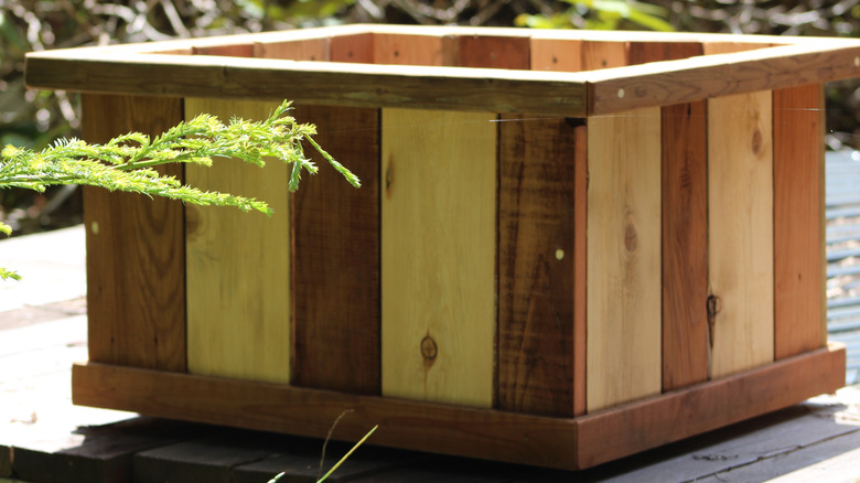 A square planter box made of cedar and redwood sittingon a deck