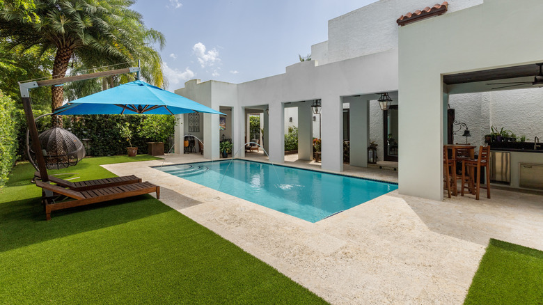 A backyard pool with an aritifial lawn