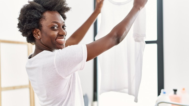 Smiling woman holding up white shirt