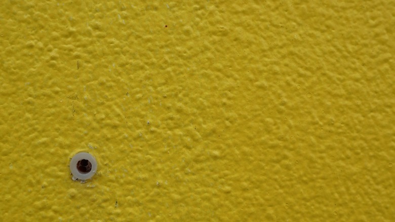 Hole in yellowish wall with drywall anchor