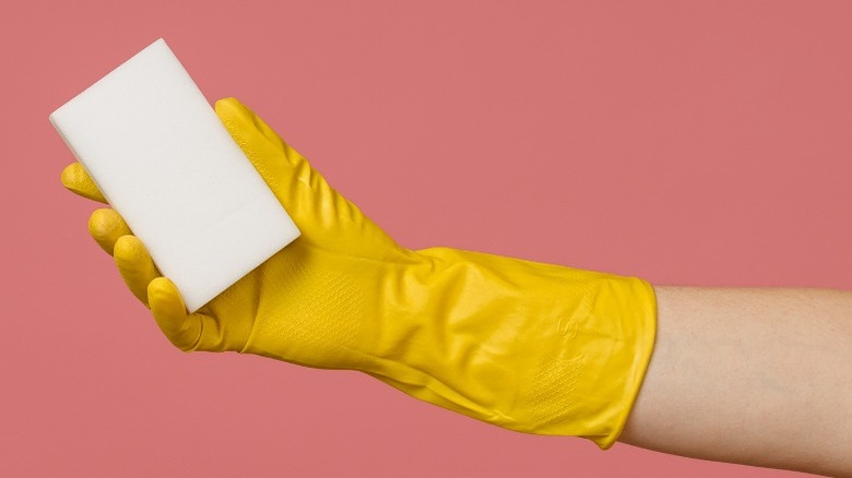 yellow gloved hand holding magic eraser