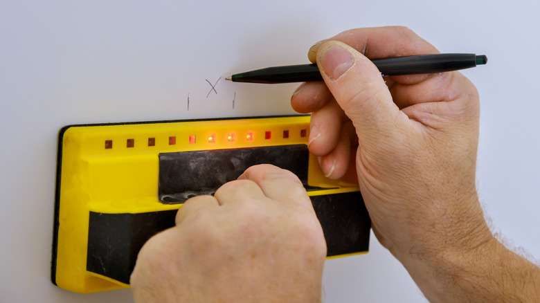 person marking wall using stud finder