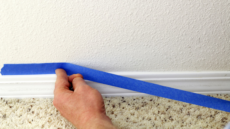 Applying painter's tape to baseboard