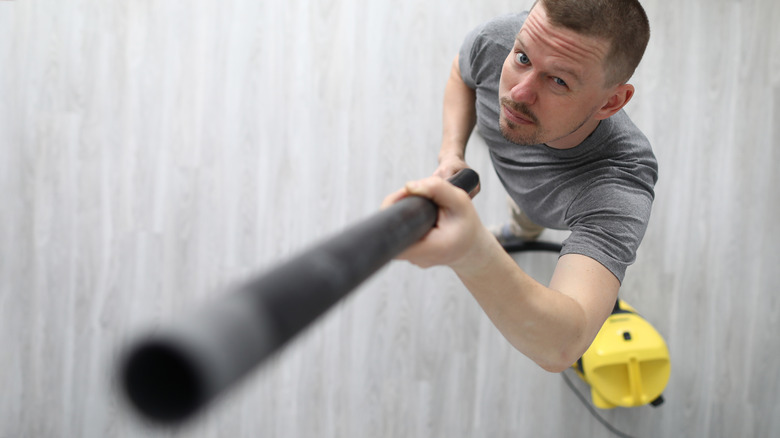 man holding vacuum attachment up