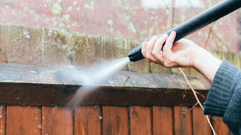 Person cleaning fence with water