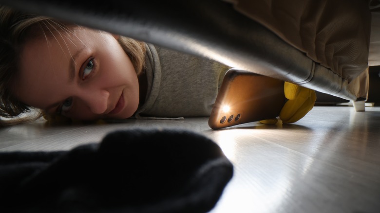 woman looking under couch