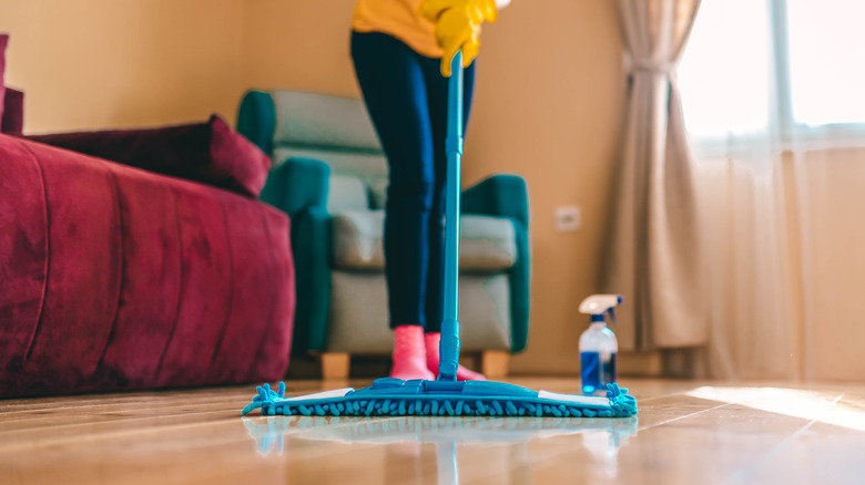 Waist-down view of person cleaning hardwood floor with a soft blue mop