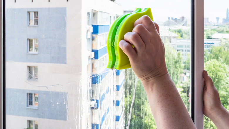 person using magnetic window cleaner