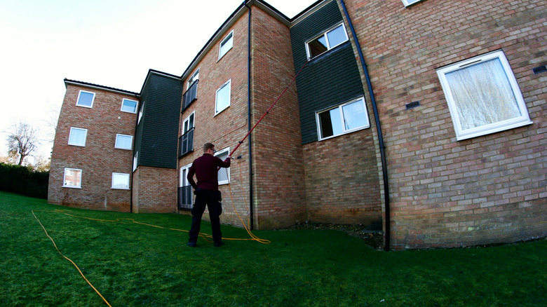 man cleaning window with a pole