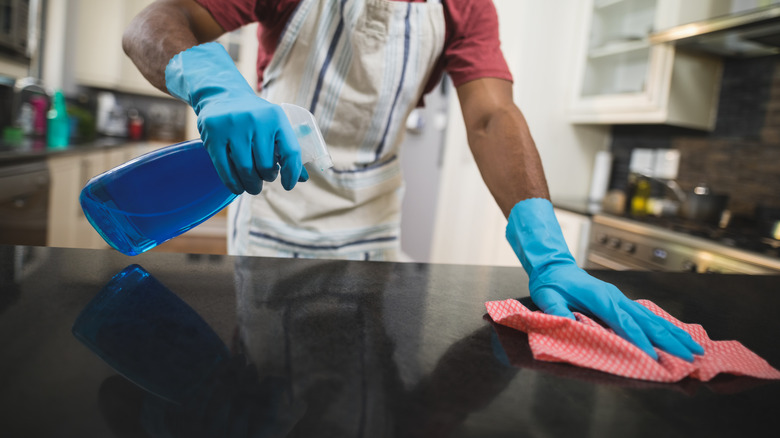 man cleaning black marble countertop