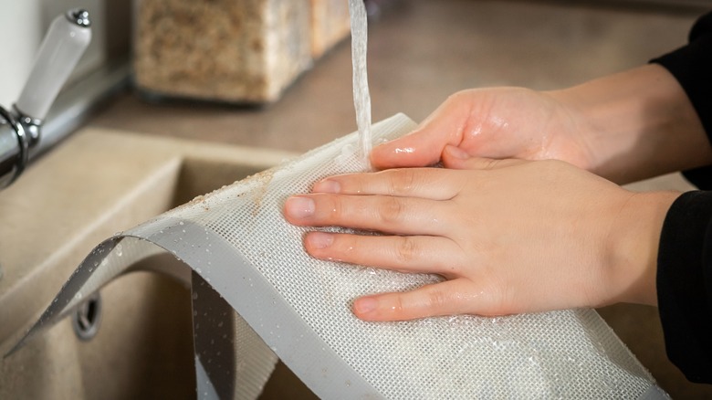 man washing silicone baking mat