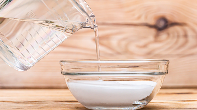 hand pouring water into baking soda