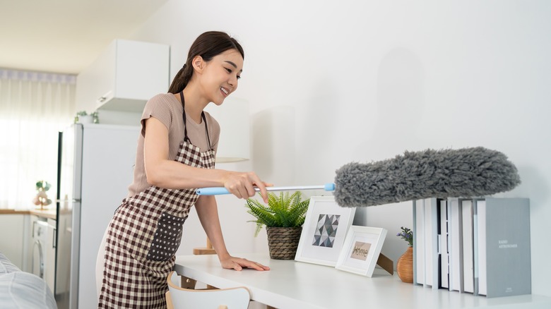 woman dusting desk with duster