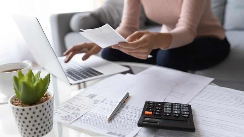 woman on couch paying bills