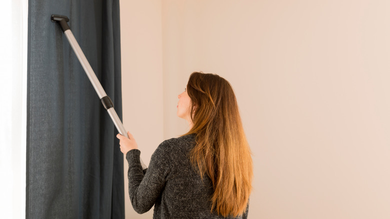 woman vacuuming curtains