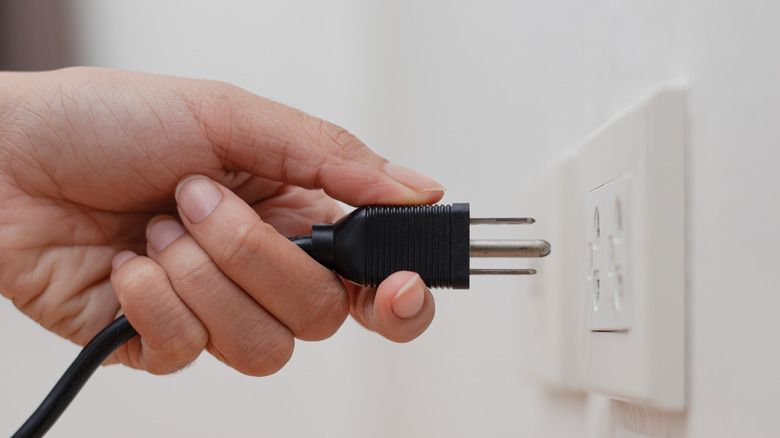 Person plugging in cord outlet