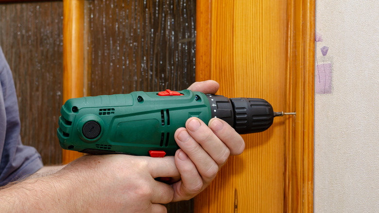 Man unscrewing wooden door frame