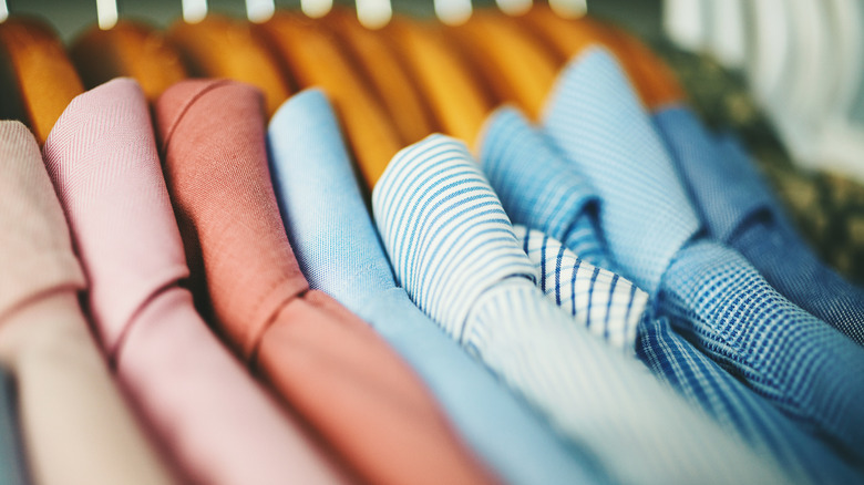 Man buttoning his shirt while standing next to rack