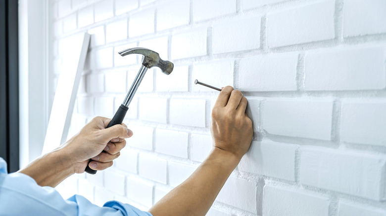 Person nailing into brick wall