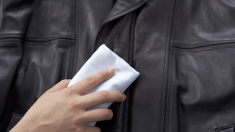 person wiping leather coat