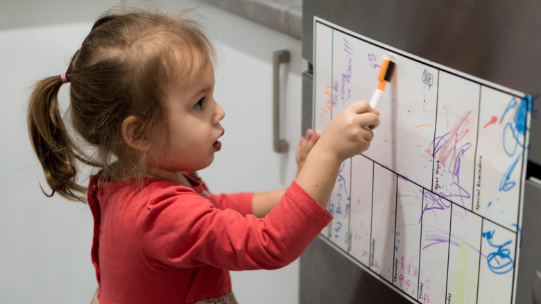 toddler writing on fridge whiteboard