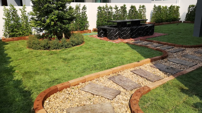 A gravel landscape pathway lines a yard